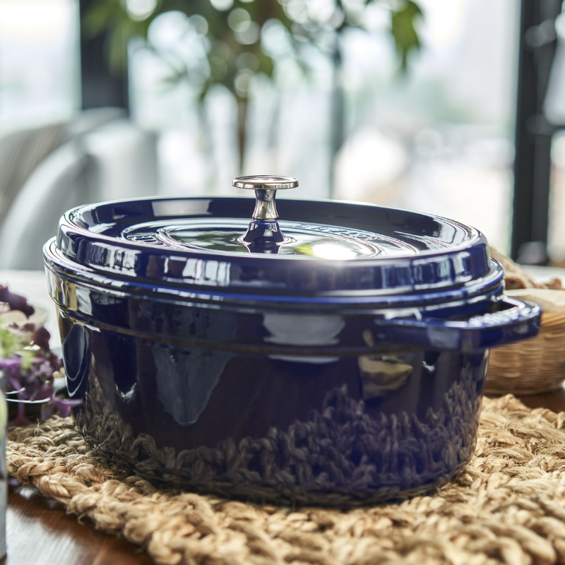 Cocotte Staub en fonte émaillée bleu foncé avec couvercle sur table en bois