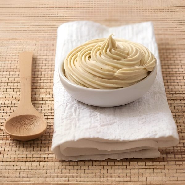 Crème diplomate à la vanille dressée en spirale dans un bol blanc sur linge beige