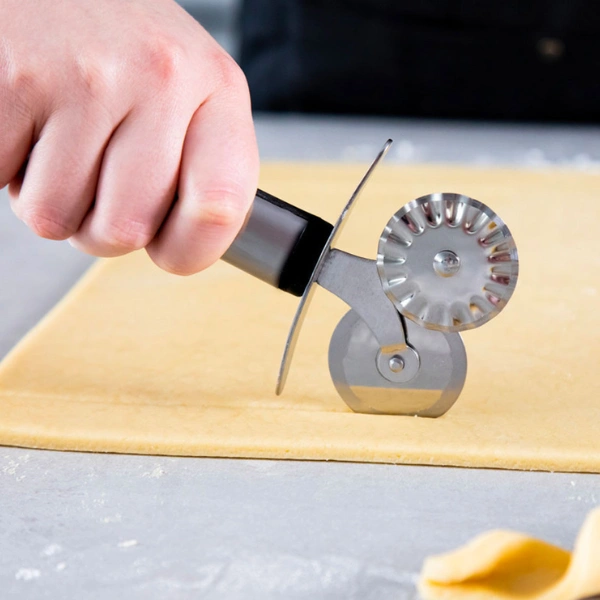 Découpage de pâte avec une roulette à pâtisserie dentelée en inox