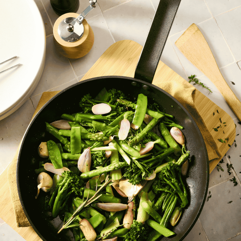 Poêle céramique De Buyer avec légumes verts en cuisson sur plan de travail