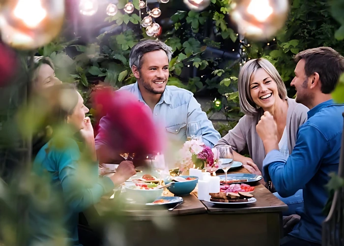 Groupe d'amis souriants partageant un repas convivial en extérieur, ambiance chaleureuse et estivale