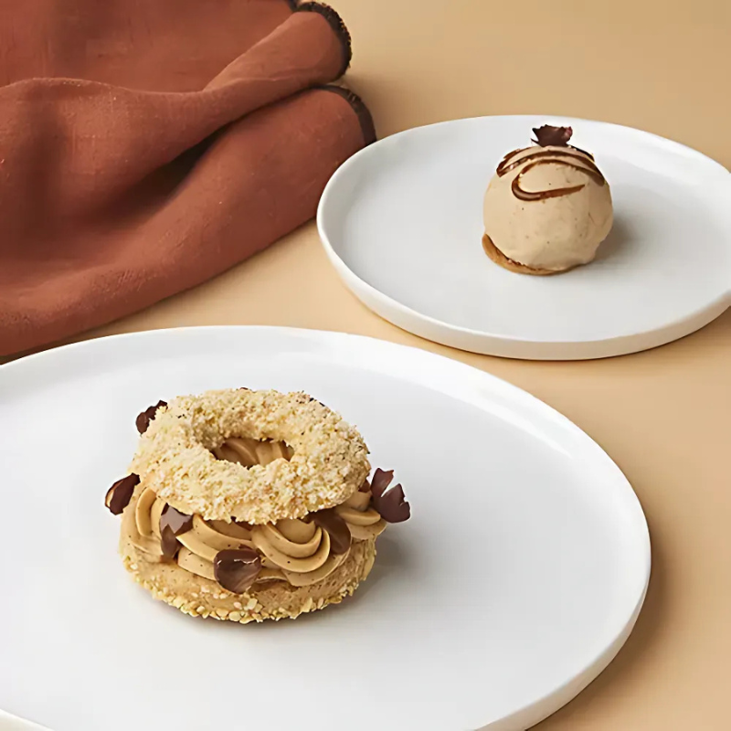 Paris-Brest à la noisette du Piémont IGP accompagné d’une boule de crème glacée sur assiettes blanches