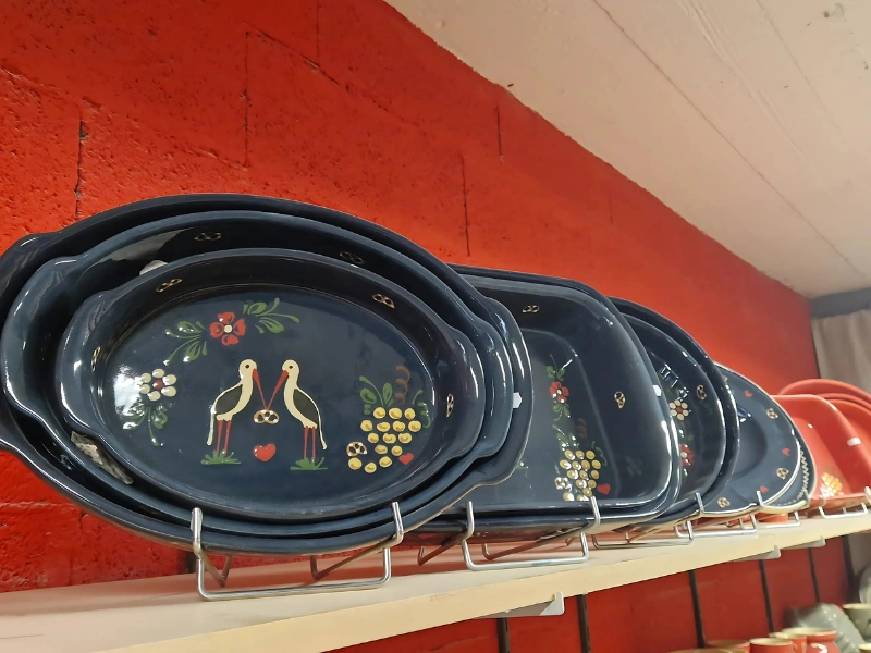 Plats alsaciens en poterie bleue décorés de cigognes, fleurs et bretzels, artisanat traditionnel